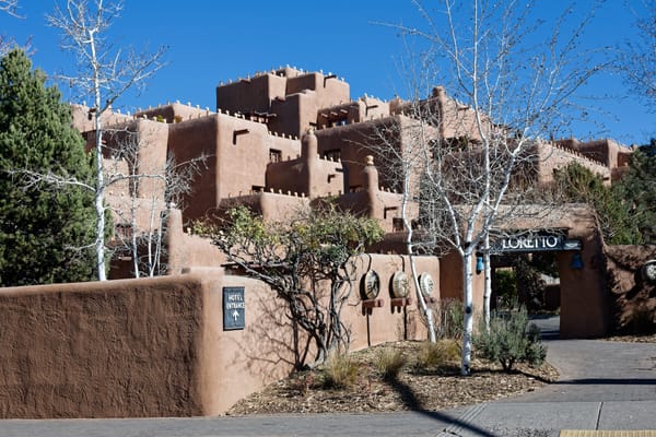 A photo of The Loretto Hotel in Santa Fe, New Mexico: a terraced Santa Fe-style hotel constructed from reddish-brown adobe.